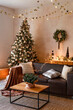 © sergiophoto - Interior of modern living room with comfortable sofa decorated with Christmas tree and gifts