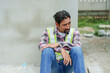 © Ekkasit A Siam - Indian foreman has mustache. Sit and relax from work. man wearing green reflective vest takes off his helmet. Sitting leaning against  cement wall after working on construction site and drinking water