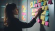 Caucasian woman organizer attaches colorful sticky notes with reminders of important things to white board.