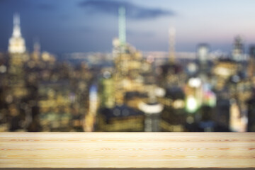 Wall Mural - Empty wooden tabletop with beautiful blurry skyscrapers at evening on background, mock up