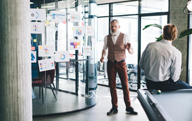 Wall Mural - Confident coworkers having conversation in modern office corridor