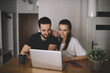 © BullRun - Positive young couple browsing laptop at home