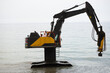 Yellow excavator working at sea