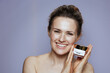 © Alliance - happy modern woman with cosmetic cream jar