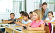 © JackF - Kids sitting at desks in classroom during their lesson. They holding phones in hands.