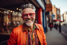 Handsome Middle-aged Man With Gray Hair And Beard Wearing Orange Jacket And Red Eyeglasses On The City Street.