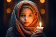 Portrait of a cute, lovely little girl with a headscarf holding a candle in a church