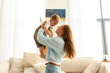 mother plays and rejoices with her little son at home, a young woman lifts her child up and laughs together