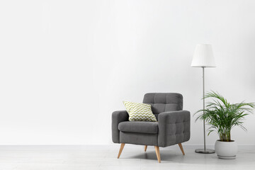 Sticker - Stylish living room interior with comfortable armchair, houseplant and lamp near white wall indoors. Space for text