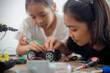 © FAMILY STOCK - nventive kids learn at home by coding robot cars and electronic board cables in STEM. constructing robot cars at home