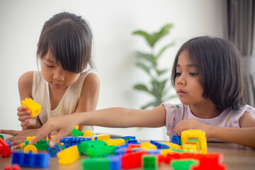 Wall Mural - Adorable little girl playing toy blocks in a bright room