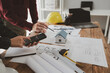 © Chadaporn - Architects and engineers work together to come up with solutions to house building problems, The property is about to be designed by a group of engineers, Architects are reviewing plans together.