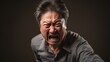 Unhappy expression angry, upset, frustrated, doubt face of Asian man on dark background, middle shot of middle-aged male shouting, yelling, extremely unhappy with wrinkles on face looking at camera