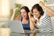 © Antonioguillem - Two excited friends celebrating news on laptop