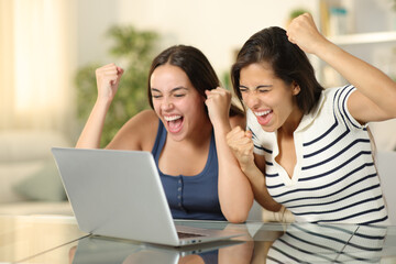 Wall Mural - Two excited friends celebrating news on laptop