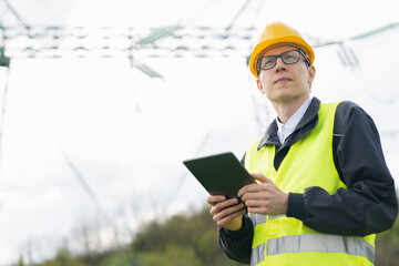 Poster - Engineer with digital tablet on a background of power line tower.