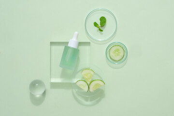 Wall Mural - Scene for advertising cosmetic of natural extract. Cucumber slices in petri dish with glass dropper on podiums on green background. The perfect natural ingredients for glowing and healthy skin.