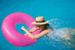 © Westend61 - Woman wearing sunglasses swimming with inflatable swim ring in pool