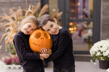 Happy Brother And Sister Holding Carved Pumpkin Together