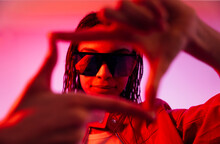 Young Woman With Sunglasses Making Finger Frame In Illuminated Tunnel
