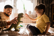 Father And Son Playing With Stuffed Toy At Home