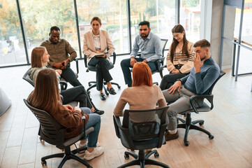 On the chairs. Group of people are having therapy meeting together