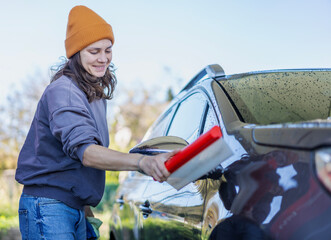 Woman wiping down car after washing car at self-service station