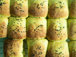 Wall Mural - top view of golden brown baked green dinner roll bread with black sesame seed topping