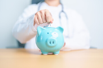 Doctor holding piggy bank and putting coin. and Healthcare cost, Money Saving, Health Insurance, Medical, Donation and Financial concepts