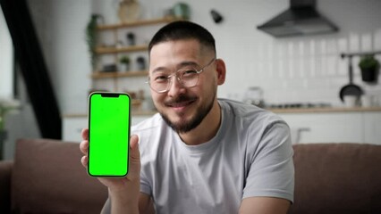Man Showing Cellphone Green Screen At Camera. Smiling Asian man holding smartphone chroma key screen at camera. 