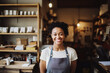 Black small business owner smiling cheerfully in her shop. Portrait of proud female shop owner in front of stacked shelves.