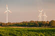 Erneuerbare und nachhaltige Energieerzeugung mit rotierenden Windrädern, im Abendlicht auf freiem Feld