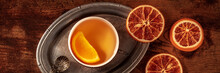 Orange Tea With Fresh And Dried Oranges Panorama, A Cup On A Vintage Tray On A Dark Rustic Wooden Background, Overhead Flat Lay Shot