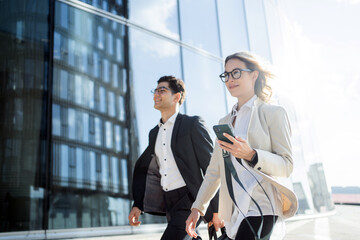 A young team of programmers or financiers in glasses go to the office business meeting a woman and a man people in business clothes smile .