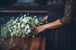 A woman is standing beside a casket with a bouquet of flowers on it.