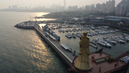 A stone Buddha gazes over Qingdao's azure waters, blending spirituality with the maritime calm.