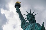 Fototapeta Miasta - Majestic Statue of Liberty illuminated against a cloudy sky.