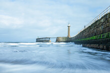 Whitby Pier With Blue Waves, Pier And Lighthouse