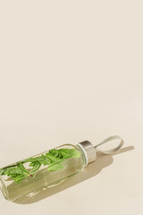 Wall Mural - Glass bottle with green mint leaves water drink detox at sunlight on beige table background, copy space, sun glare. Natural Infused water Healthy drink. Aesthetic still life, refreshing drink