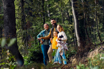 Wall Mural - Portrait of smiling family of four exploring nature on a scenic forest hike.