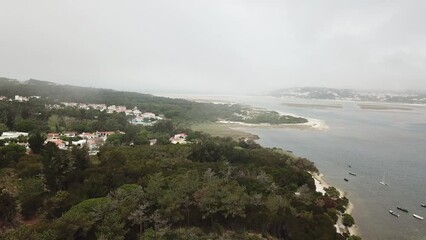 Sticker - Descending drone over green coastline by the sea with hazy cloudy sky on the horizon