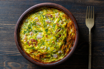 Wall Mural - Ceramic bowl with vegetable frittata, simple food. Frittata with egg, tomato, pepper, onion, shrimps and cheese on wooden table, closeup, top view. Italian egg omelette