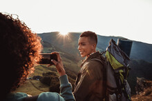 Two Female Hikers Looking At Sunset Taking Picture