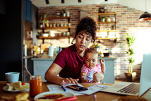 Young Mother Doing Financials With Baby At Home