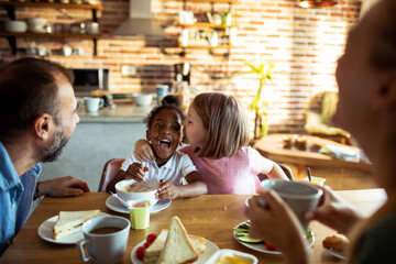 Mixed family having breakfast in the kitchen