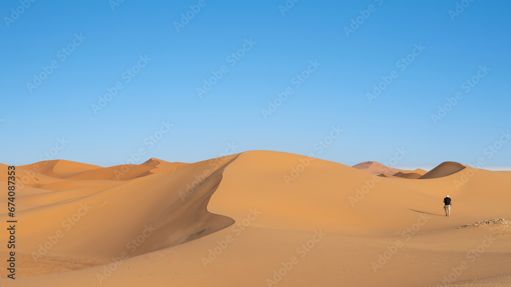 Unidentified tourist walking on sand dunes of Sahara Desert in northern ...