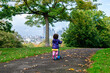 A child on a push scooter in autumn in a city park, London, England