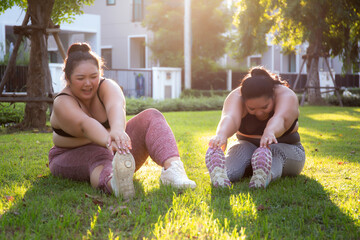 Obese two young asian woman doing stretching leg in the park, woman with overweight warm up and exercise for dieting and health, workout and motivation, oversized and challenge, plus size.