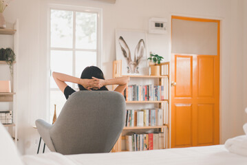 Wall Mural - Relax women sitting on chair in bedroom with hands over head,Back view