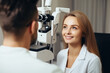 Optometrist performing an eye exam on a smiling female patient.